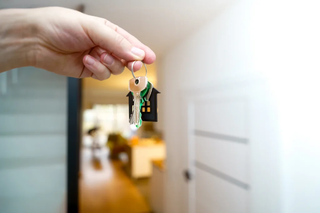 Mão segurando as chaves na porta de entrada de um apartamento novo